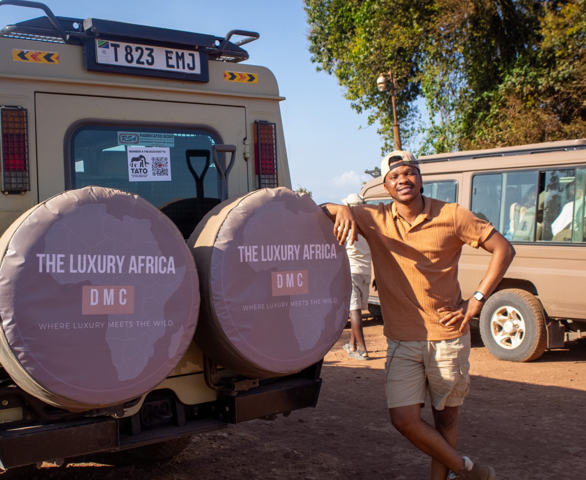 A member of The Luxury Africa DMC field team beside branded safari vehicles