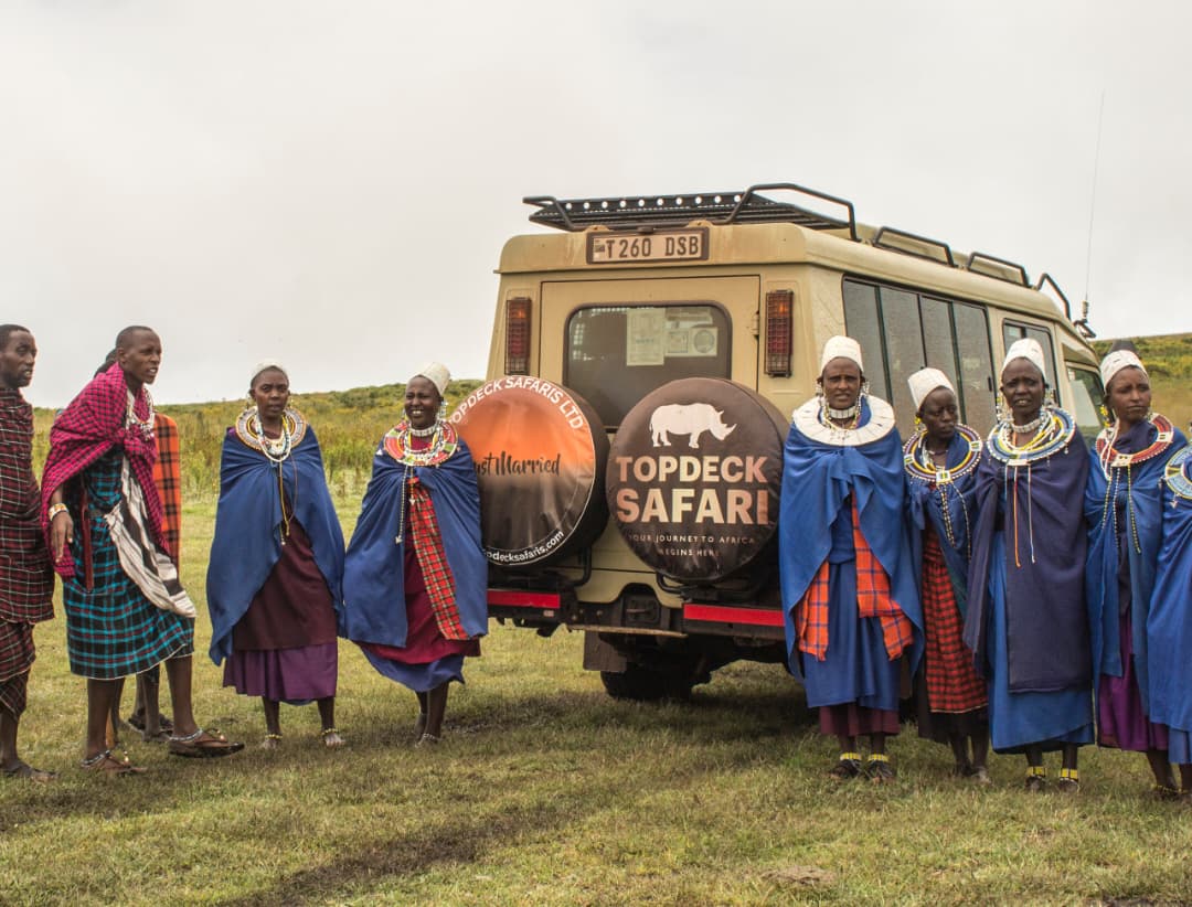 Local community members standing beside a safari vehicle in Tanzania