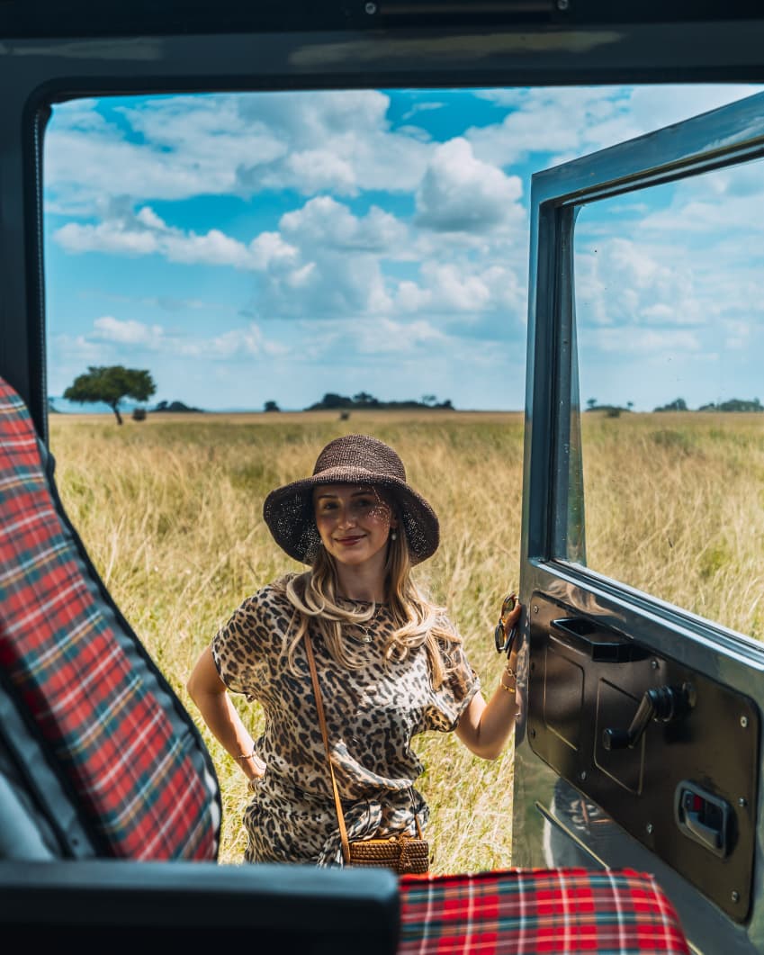 Guest standing by an open private safari vehicle in the Serengeti