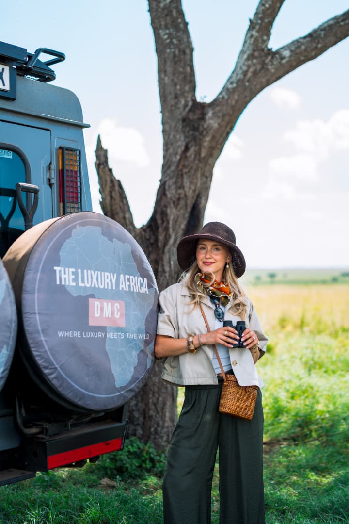 Guest beside a branded private safari vehicle in the Serengeti