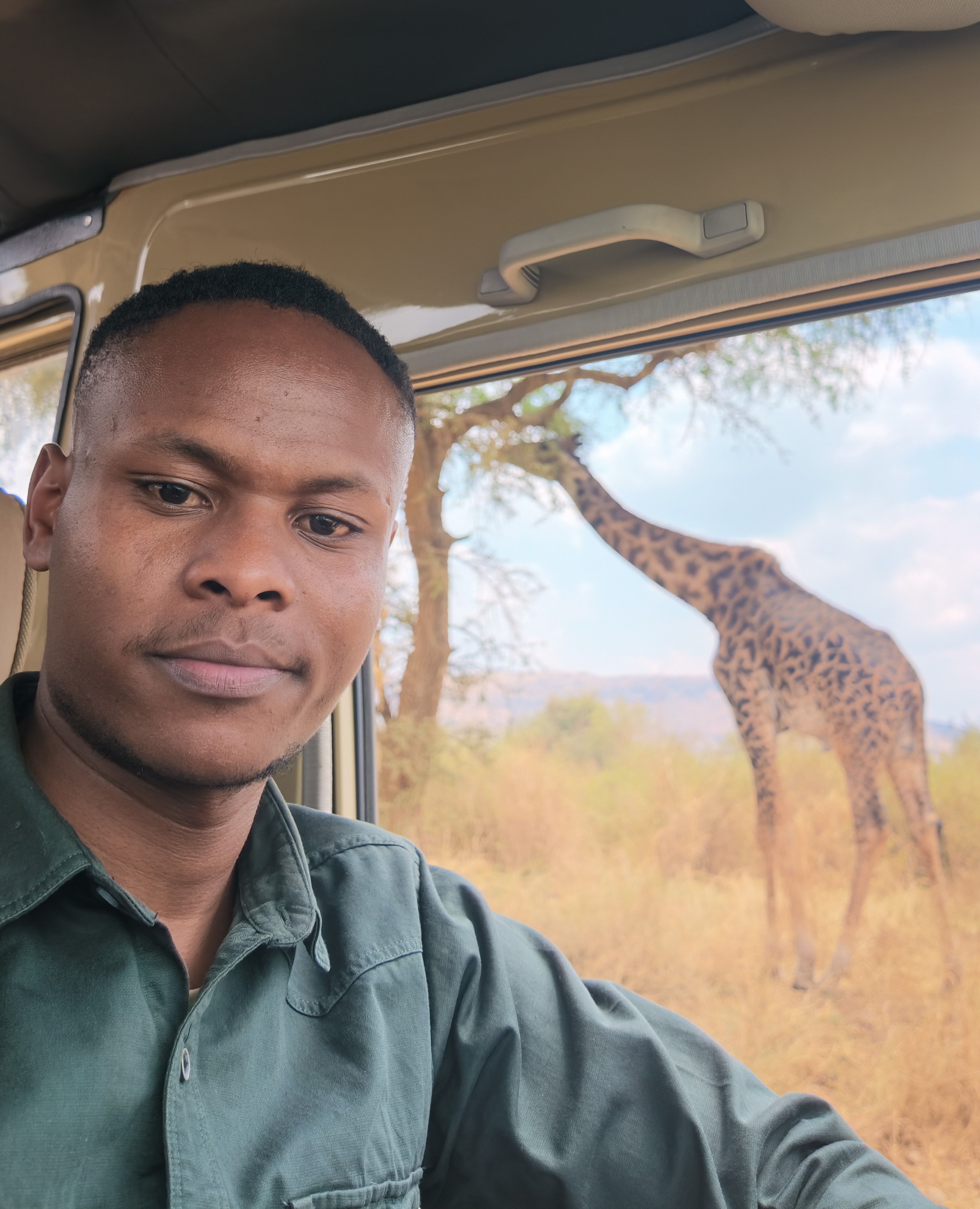 Safari guide in a private vehicle beside a giraffe